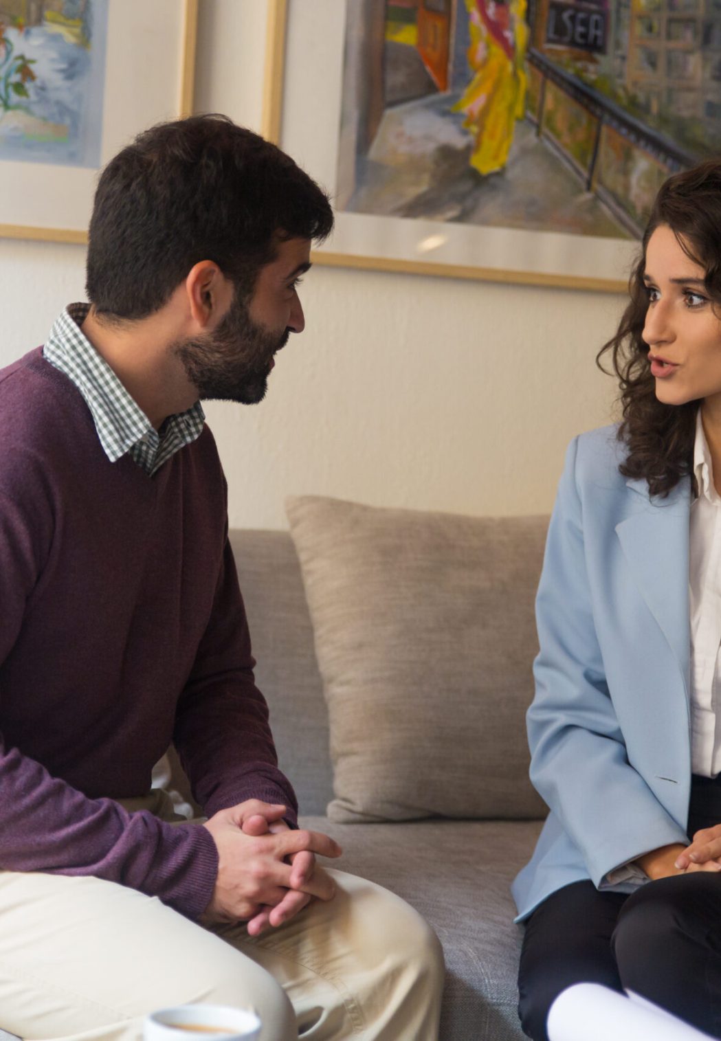 Customer and consultant meeting at home or in office and discussing deal. Young man and woman sitting on couch in living room and talking. Meeting concept